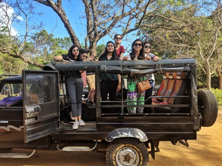 A group of girls in a safari jeep with trees in the background