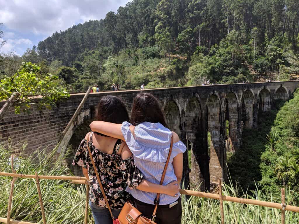 2 girls with their backs towards the camera, looking on to Nine Arches Bridge in Ella Sri Lanka 