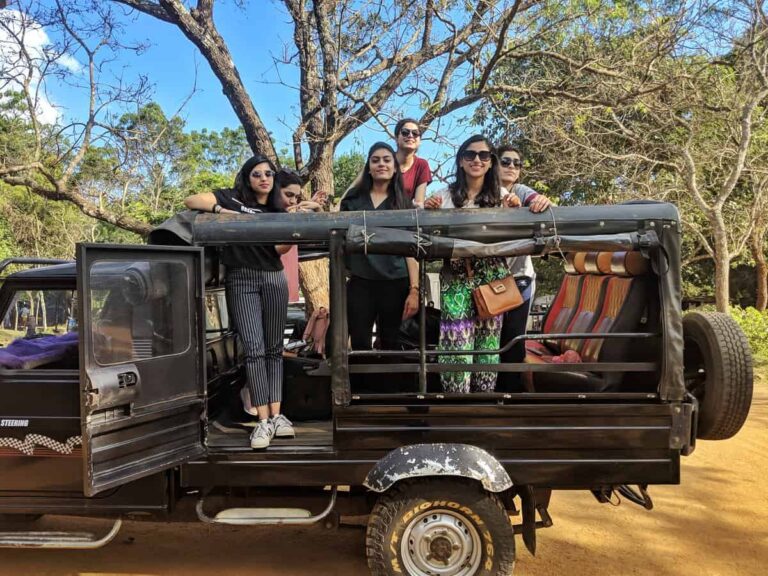 A group of girls in a safari jeep with trees in the background