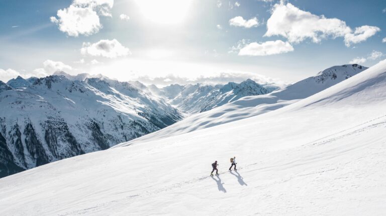 Zoomed out image of snowy mountains and 2 people skiing in pakistan the middle