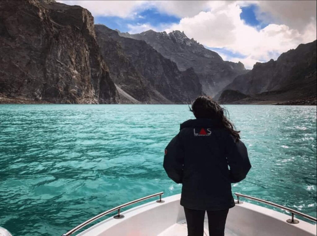 A girl standing with her back to the camera on a boat at attabad lake