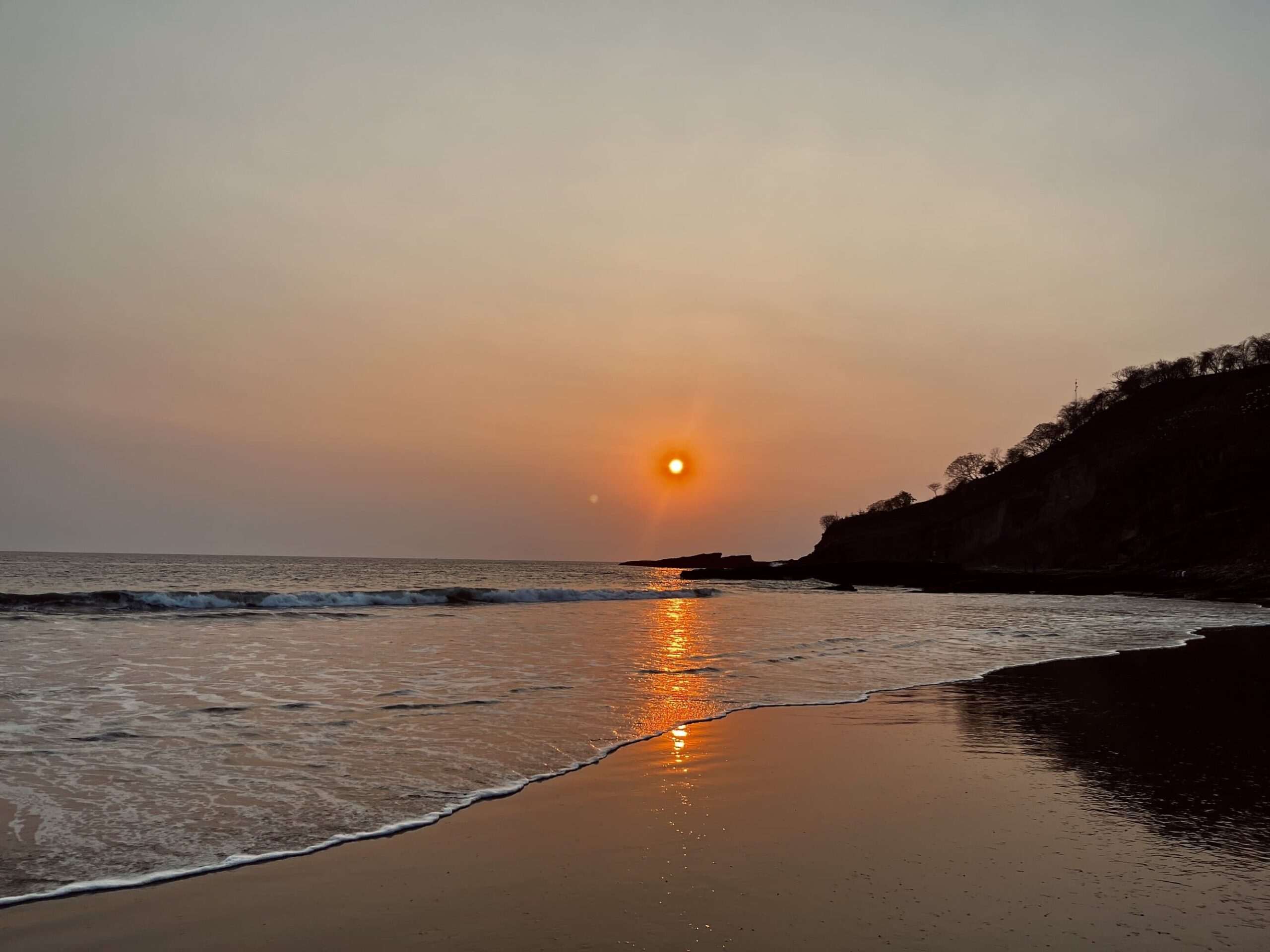 Golden sunset over the beach in San Juan del Sur, Nicaragua, with gentle waves.