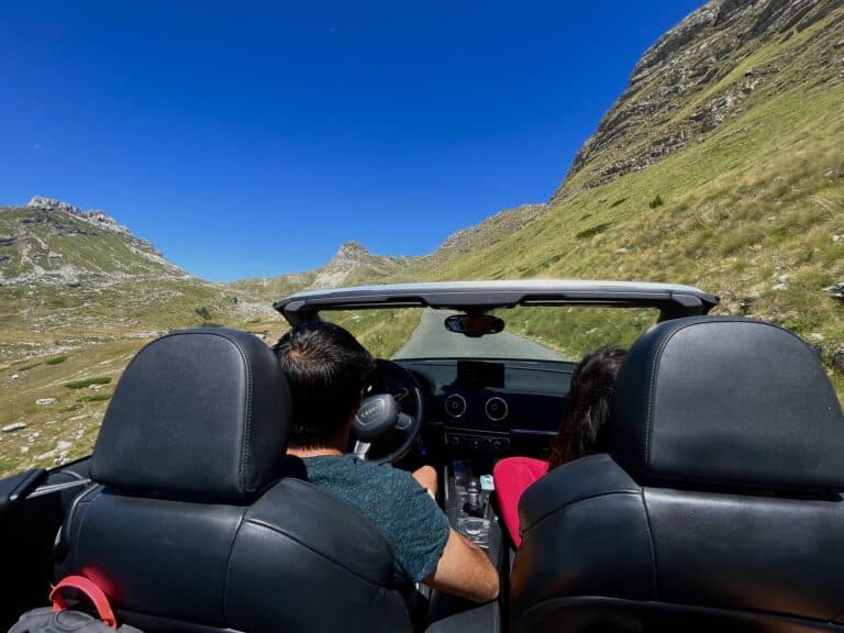 Picture of a two passengers in a car, on a mountain road highlighting the benefit of renting a car in Montenegro