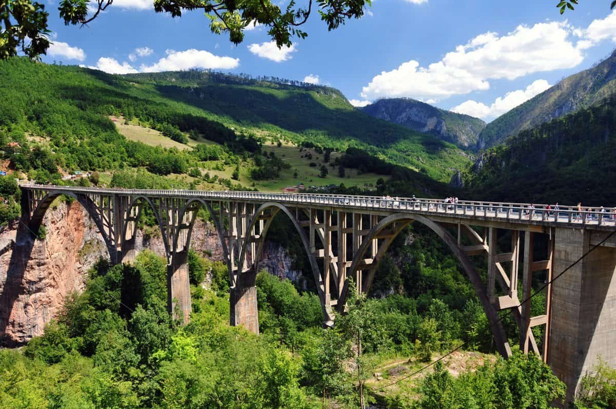 The Đurđevića Tara Bridge stretches across the deep Tara River Canyon in Durmitor National Park, surrounded by forested cliffs and rugged mountain scenery. The bridge highlights one of Montenegro's most dramatic viewpoints and the starting point for popular activities like ziplining and white water rafting.
