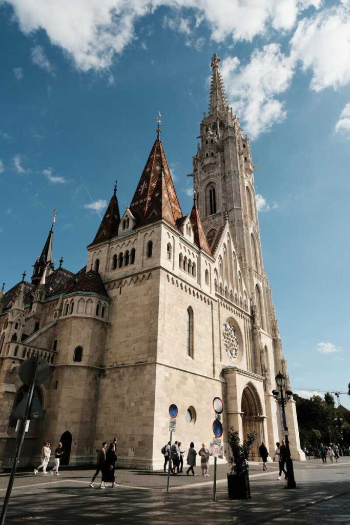 Matthias Church stands out with its colorful tiled roof and gothic spires against a blue sky. The ornate details and vibrant patterns make it one of Budapest’s most iconic landmarks.