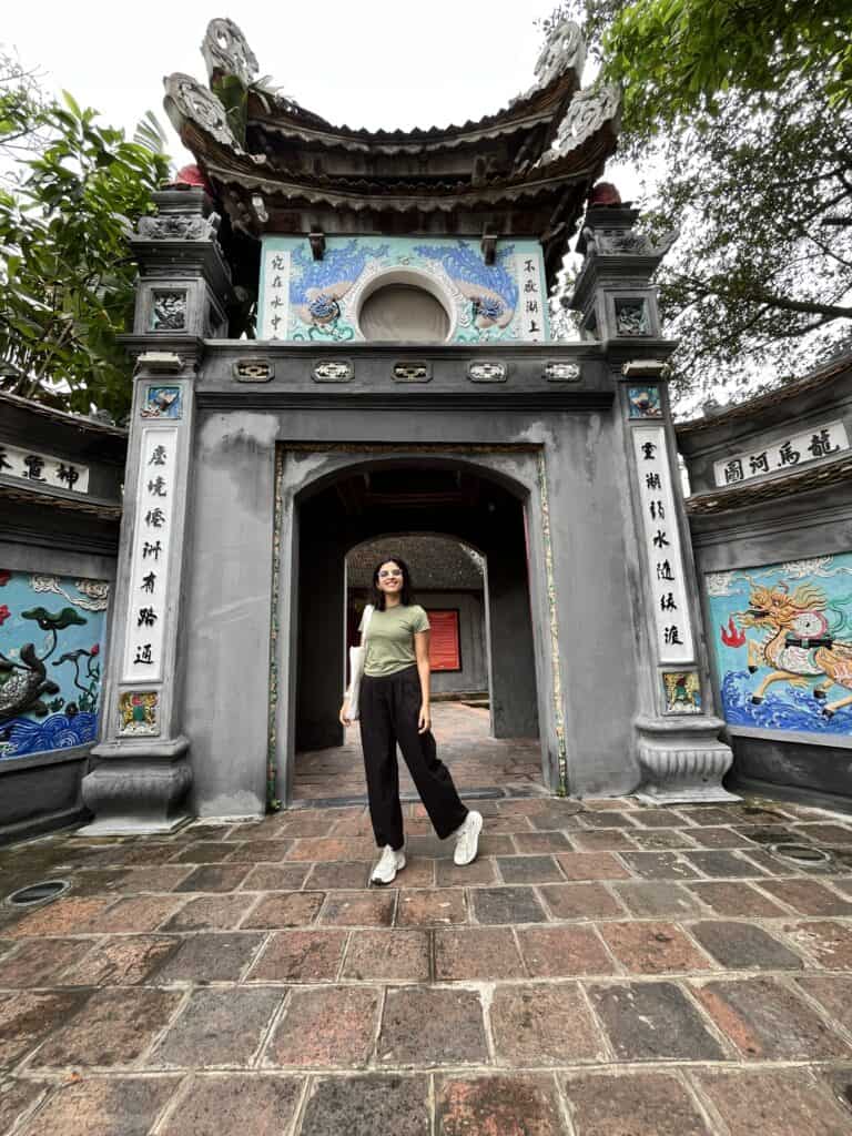 A girl standing in front of the gate of a Ngoc San Temple