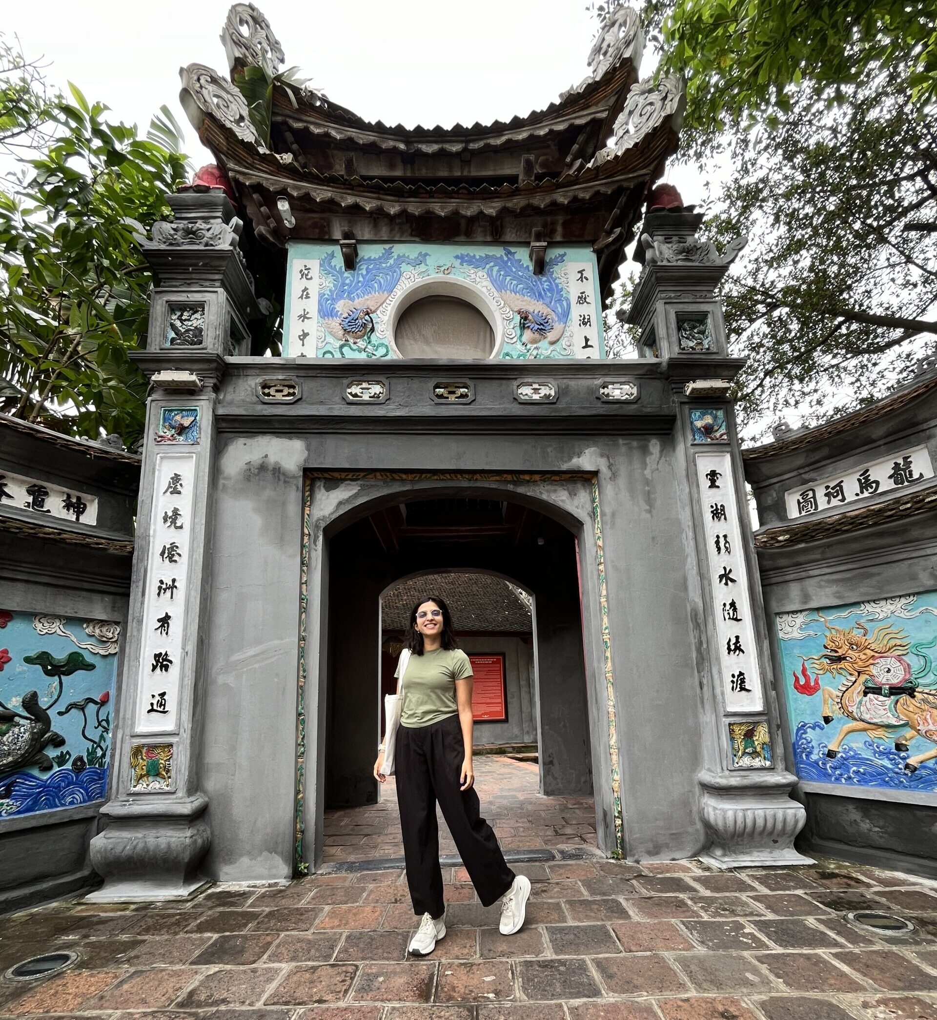 A girl standing in front of the gate of a Ngoc San Temple