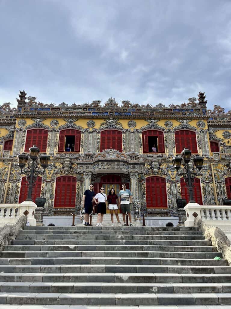 4 people in front of a red and yellow palace