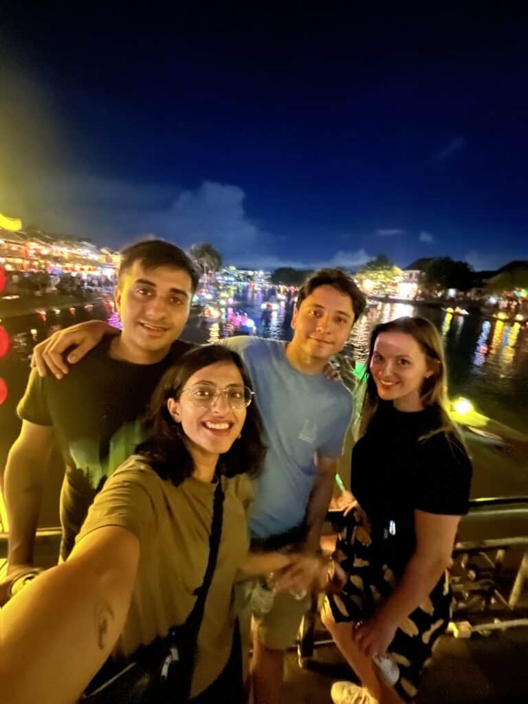 Zoomed out selfie at a birdge with lanterns floating in the river in the background