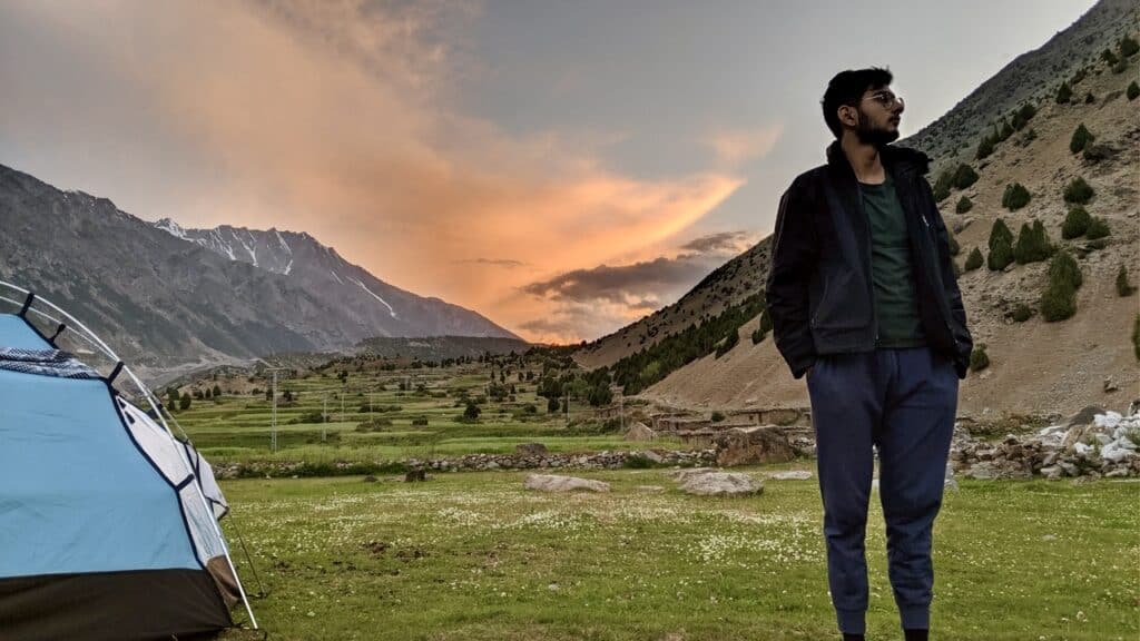 Man standing with a tent set up in the mountains