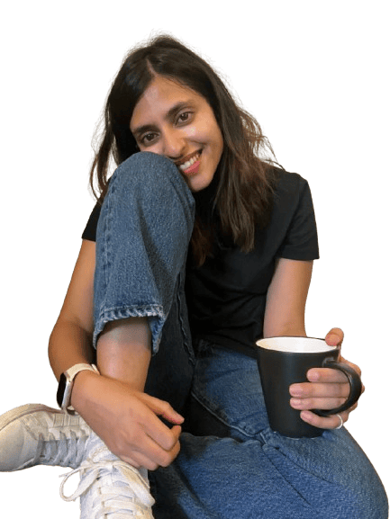 A woman sits cross-legged on the floor holding a cup of chai, with a relaxed expression and cozy setting. Used in the sidebar of Musafir in Transit blog posts, the image adds a personal, inviting touch to the reading experience.