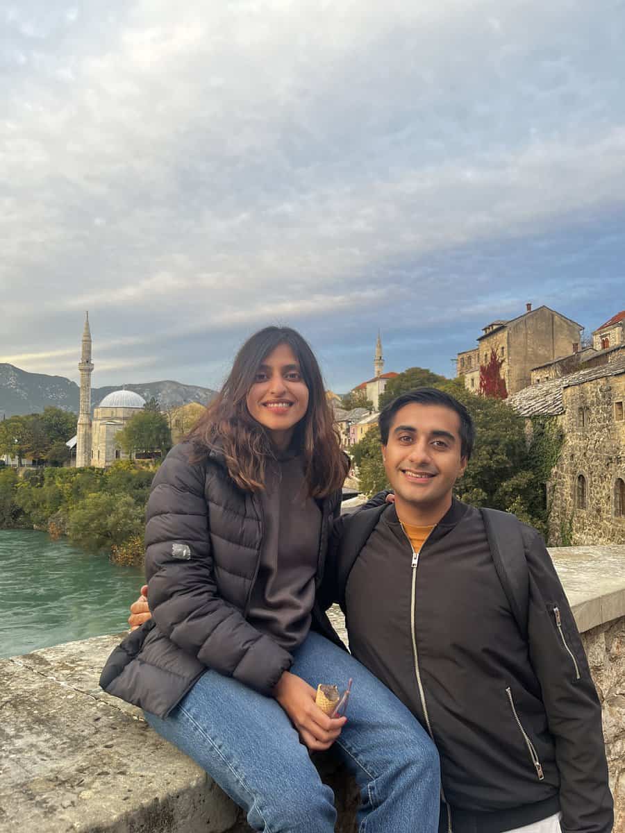 A couple standing on a bridge with a mosque in the background
