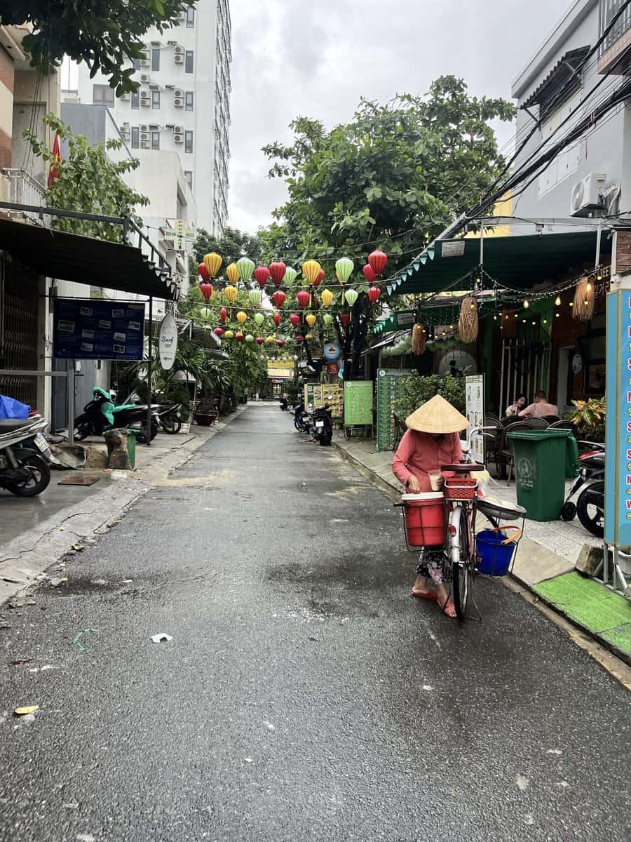 A vietnamese woman riding a bicycle, wearing the local hat