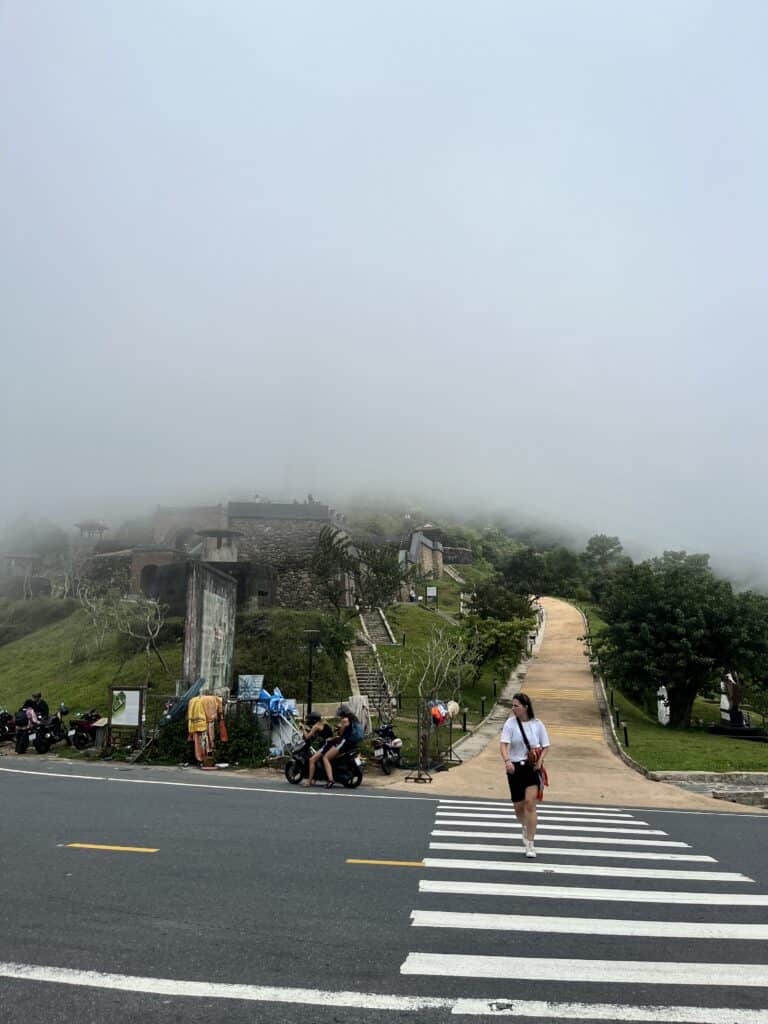 A girl crossing the the roat, with misty clouds in the back