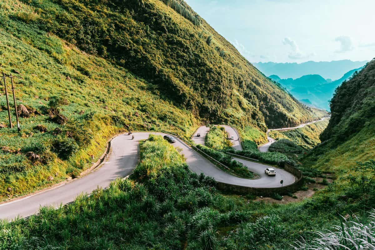 A winding stretch of the Hai Van Pass curves along the lush green mountainside, with sweeping views of the coastline below. One of the most scenic things to do in Da Nang, especially for travelers exploring by scooter.