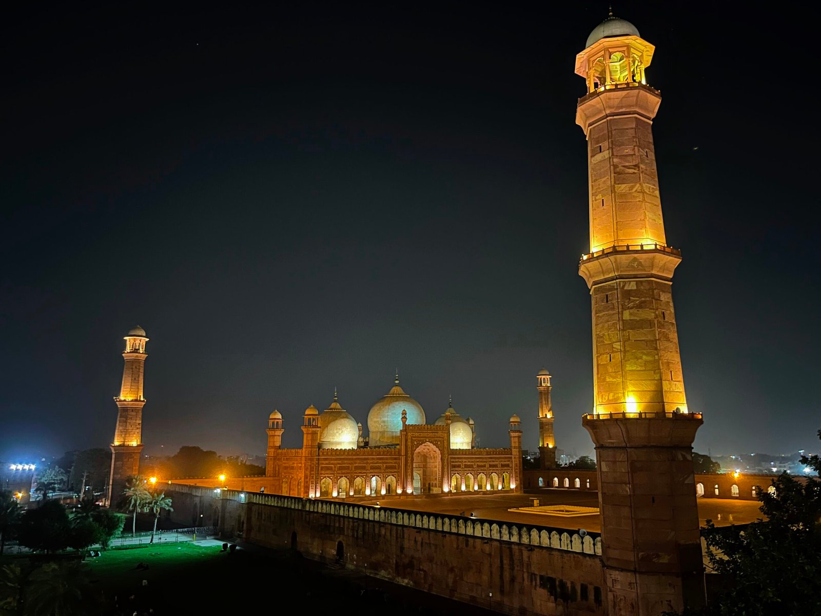 Badshahi Mosque illuminated with warm golden lights against the dark night sky in Lahore. Seeing the historic red sandstone mosque after sunset can be a memorable experience when considering the best time to visit Pakistan.