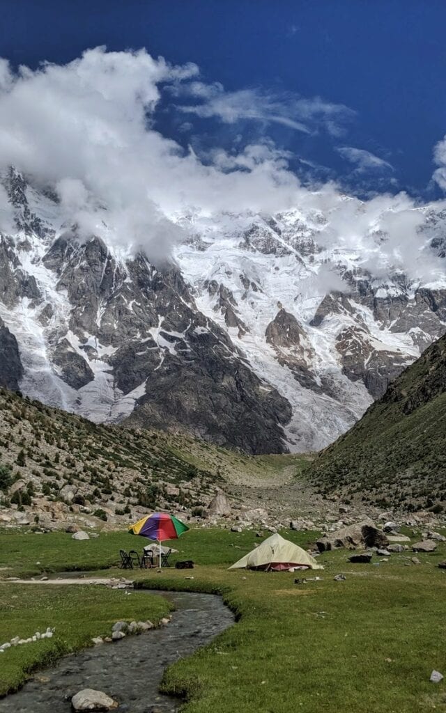 A tent and chairs set up by a stream at Herligkoffer base camp Nanga Parbat