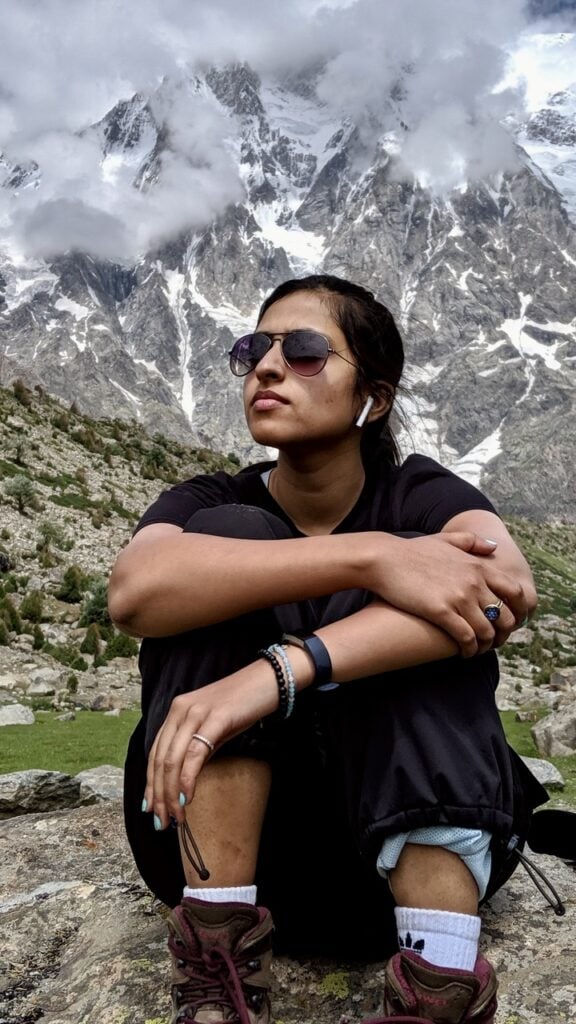  A close up of a woman sitting on a rock in front of Nanga Parbat