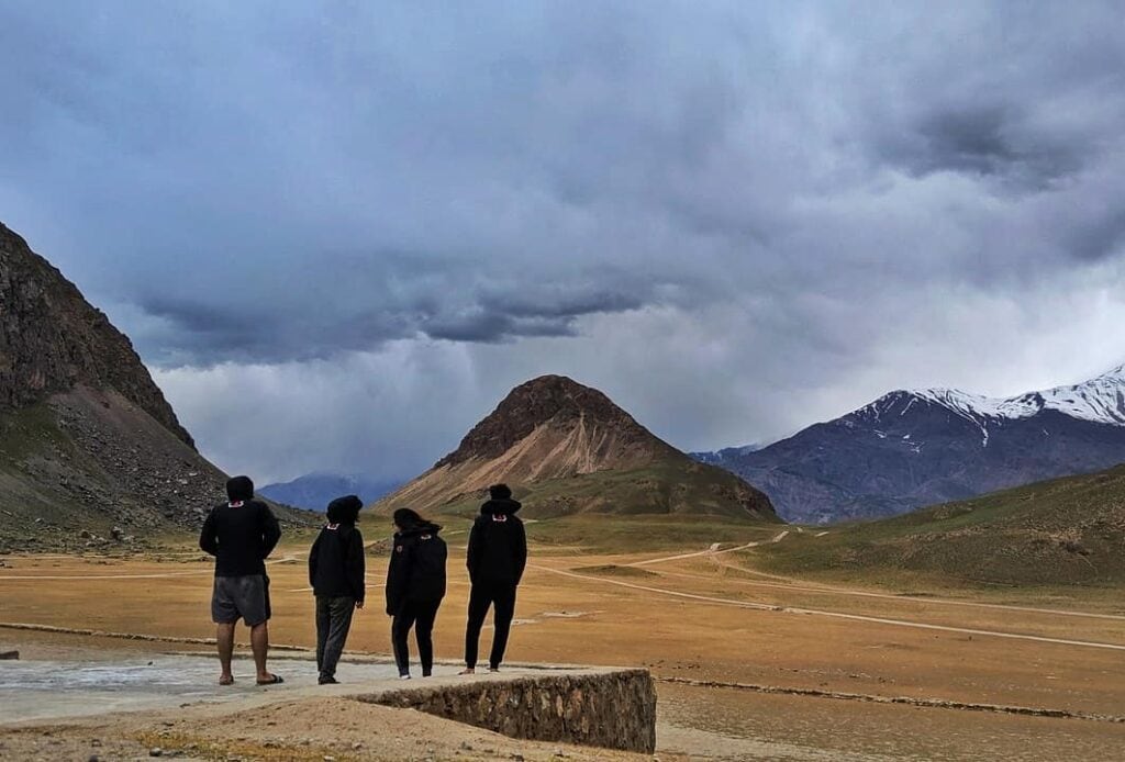 4 people standing in the meadows on a cloudy day 