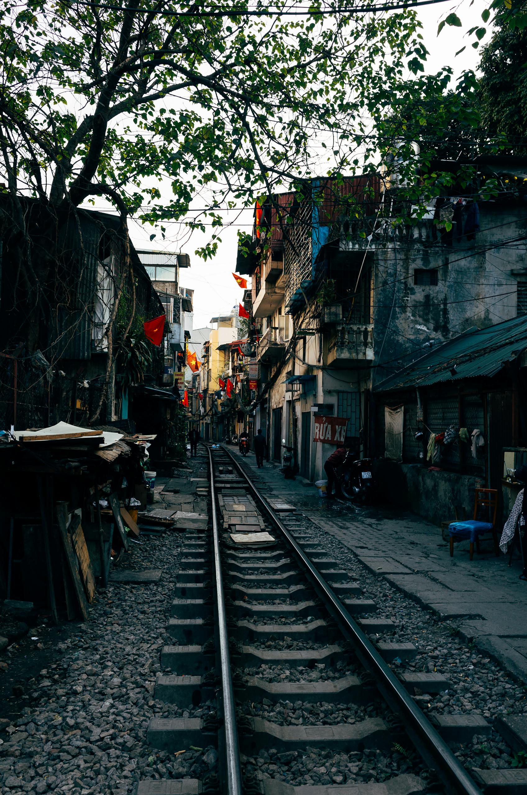 Narrow railway tracks running through a lively train street Hanoi, Vietnam, surrounded by urban life.