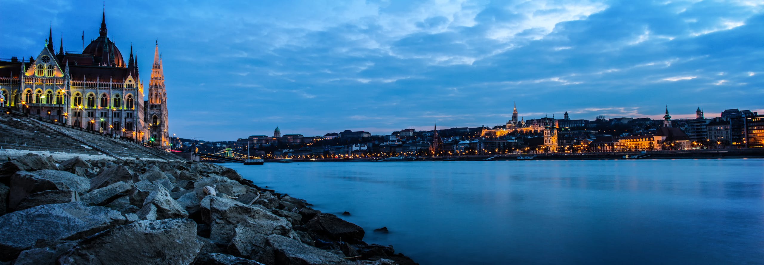 Where to stay in budapest? Scenic view of Budapest Parliament and Danube River at dusk.