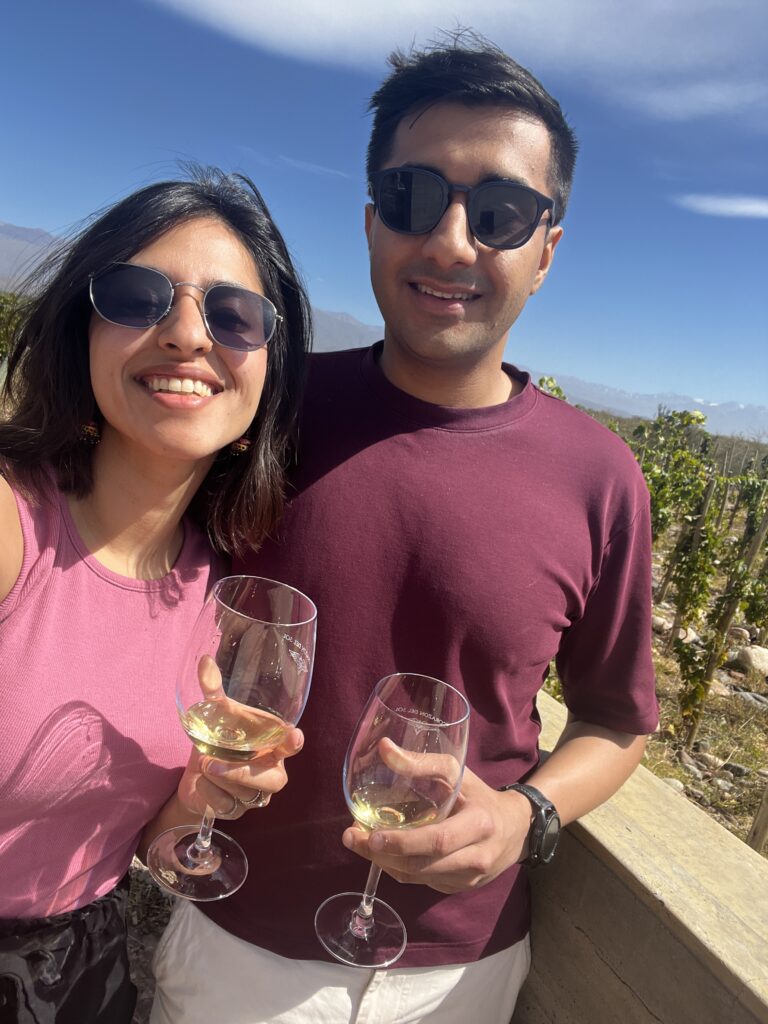 Selfie of couple trinking white wine, in the background you can see a vineyard in Mendoza, Argentina.