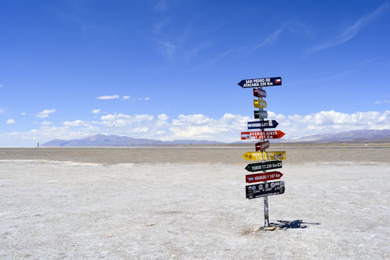 A bright signpost stands in a vast arid landscape with clear blue skies signaling placed to go add in an itinerary for Argentina.