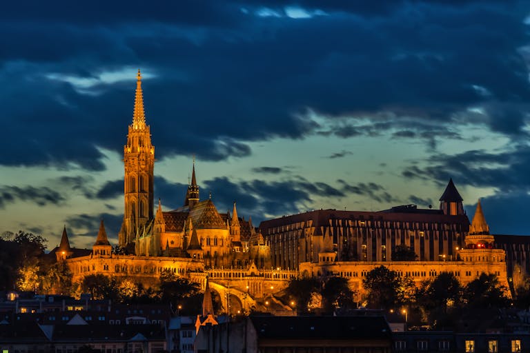 Captivating view of Matthias Church lit up at night in Budapest, Hungary. Highlighting Budapest Tour options.