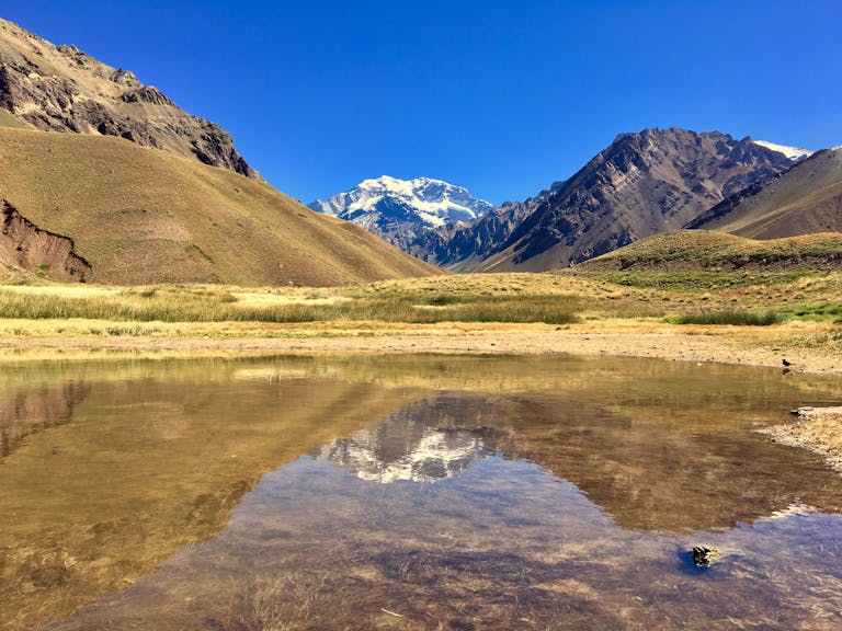 A stunning view of Aconcagua reflecting in a tranquil lake in Mendoza, Argentina, seen on the Confluencia Hike
