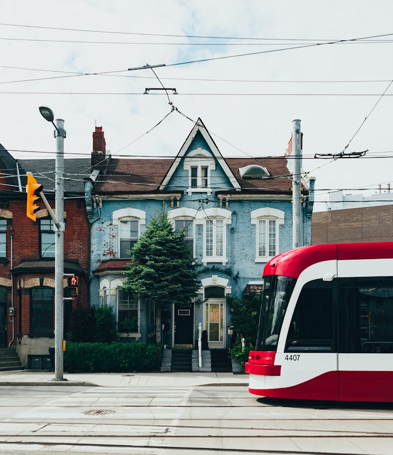 A red streetcar moves through the urban streets of Toronto, showcasing classic Victorian architecture highlighting where to stay in Toronto.