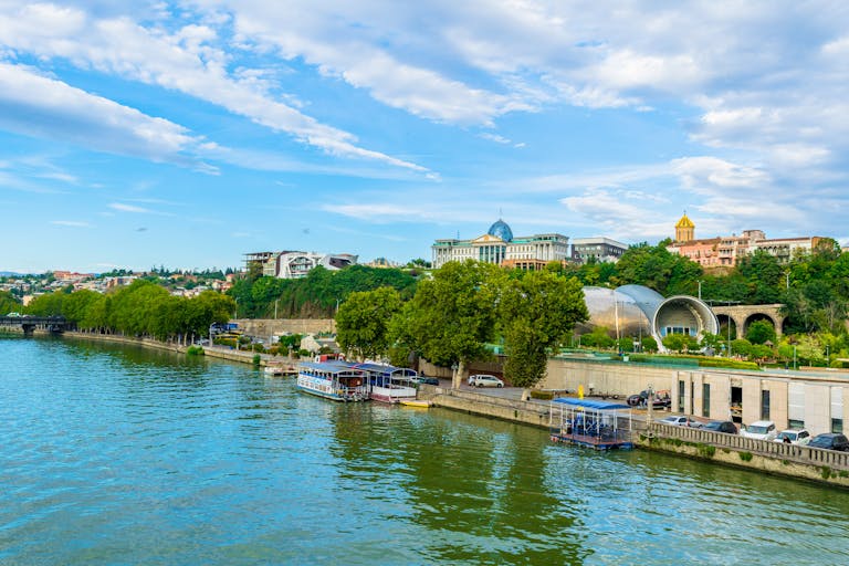 Beautiful riverside showing Tbilisi's vibrant urban architecture with ferries along the canal. Perfect show of what is included in a Tbilisi Itinerary.