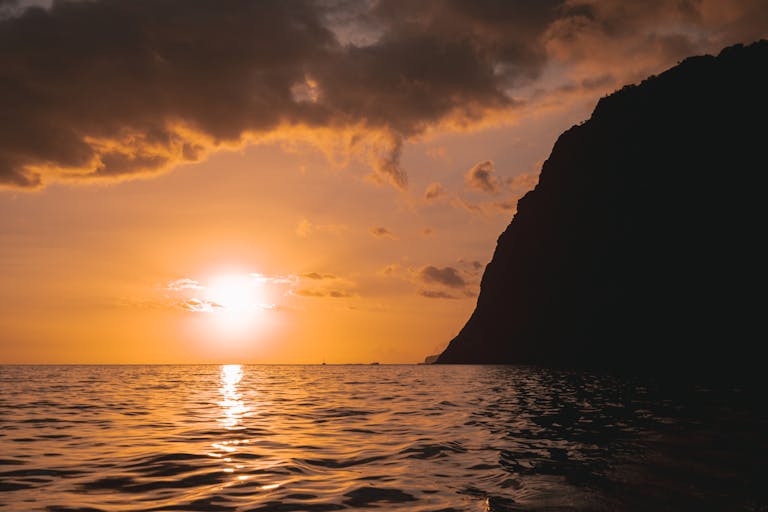 Stunning sunset view with orange hues over the ocean portraying a relaxed itinerary for Madeira, Portugal.