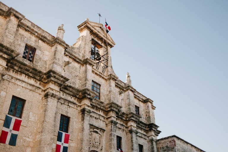 Low angle view of historic colonial architecture with flag in Santo Domingo, highlighting the contrast of places in Punta Cana vs Santo Domingo