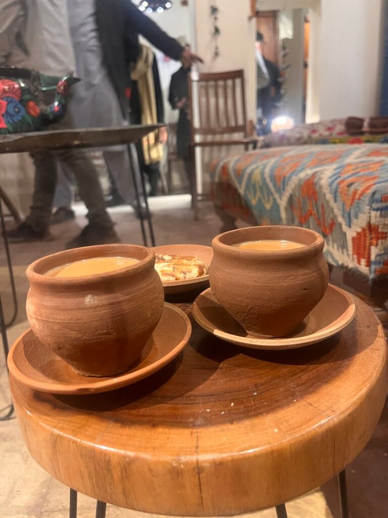 Two small clay cups filled with hot chai sit on a wooden surface in Old Lahore with steam rising gently. The setting reflects a quiet moment of traditional tea culture in the historic part of the city.