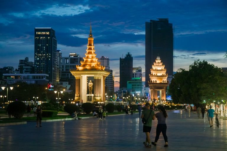 Illuminated Norodom Sihanouk Statue in Phnom Penh during night, with people walking nearby, highlighint neighbourhoods of where to stay in phnom penh